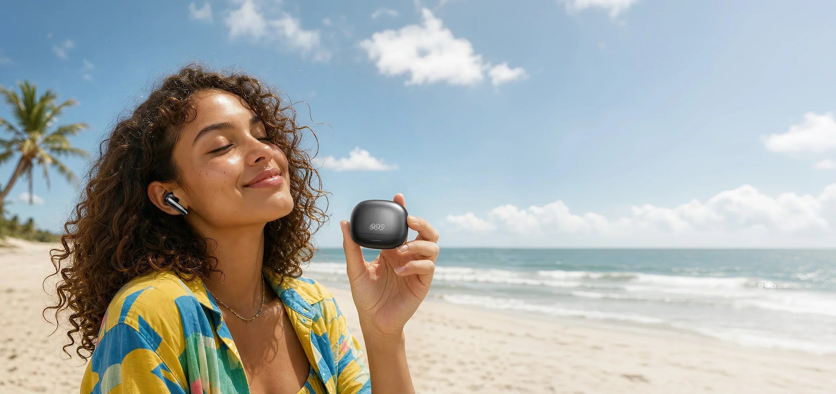 Mulher na praia com fones QCY e case, curtindo som sem fio. Ideal para explicar modo de baixa latência em produtos de áudio.