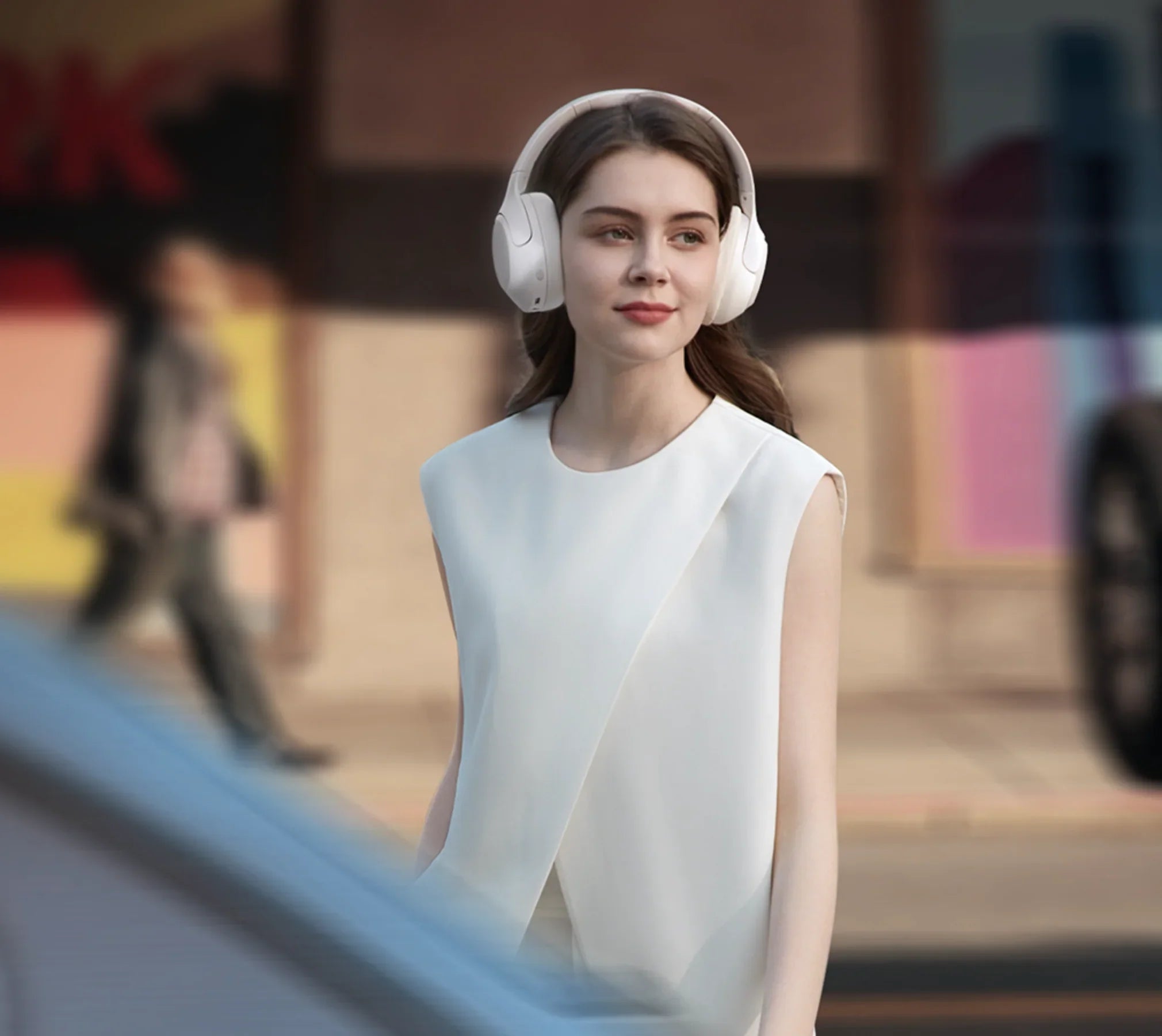 Mulher usando fones de ouvido brancos sem fio em ambiente urbano, estilo moderno e elegante.