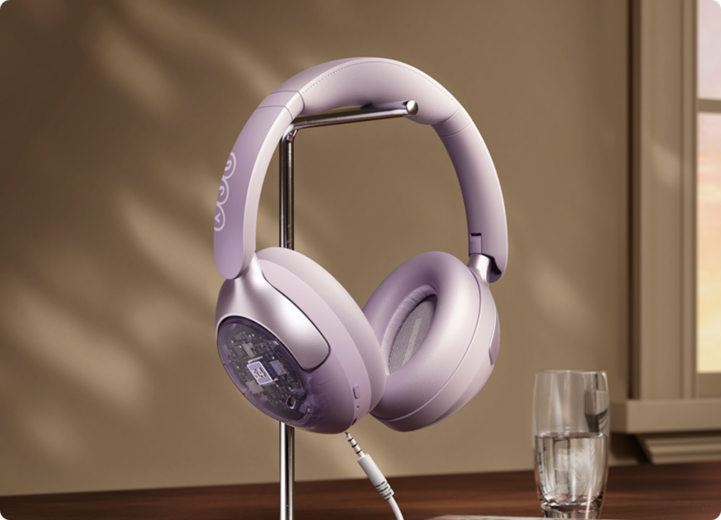 Fone de ouvido sem fio lilás em suporte metálico, com design moderno e detalhe transparente no auricular.