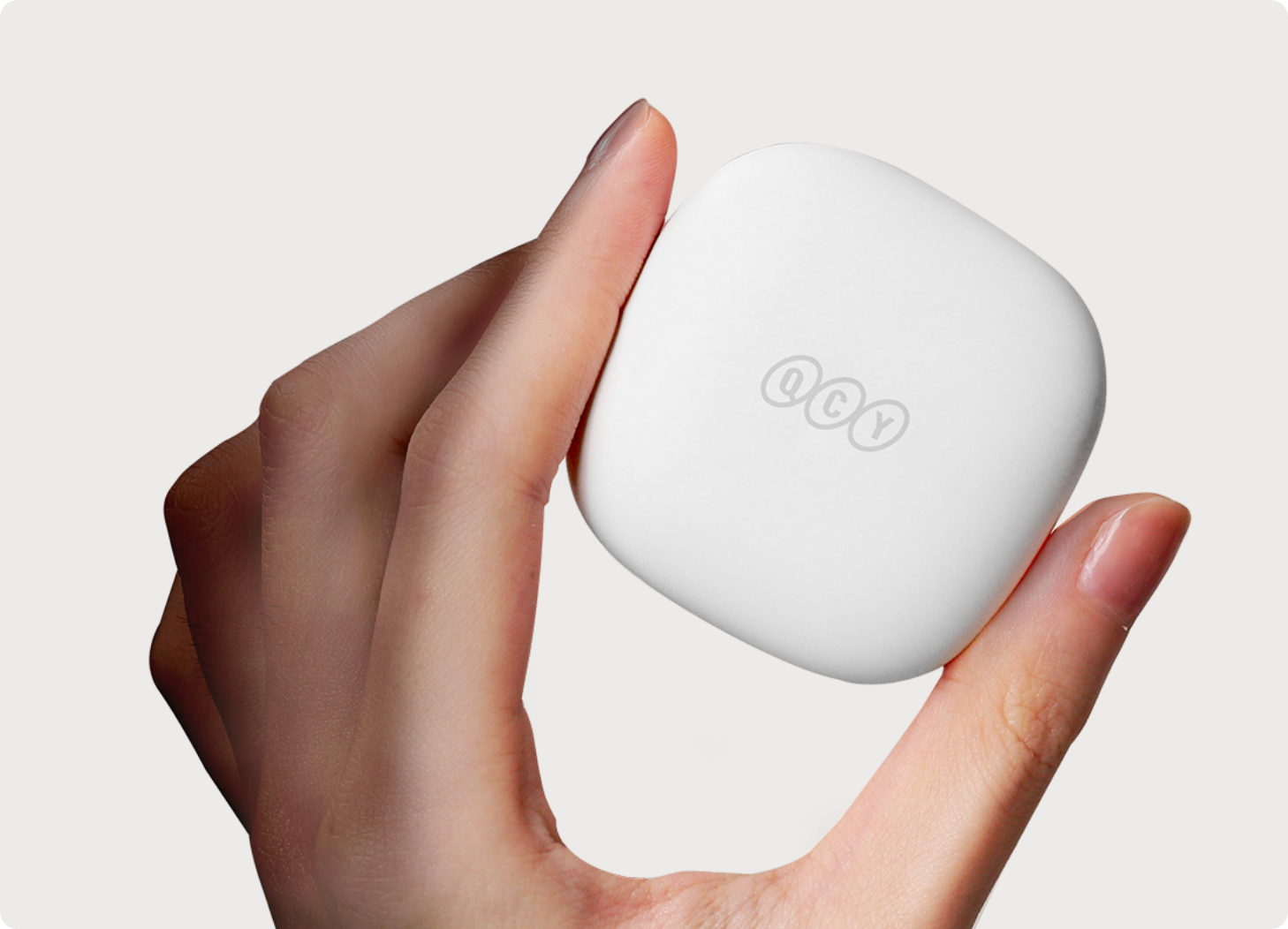 Estojo de carregamento branco QCY para fones de ouvido sem fio, segurado na mão. Design compacto e elegante.
